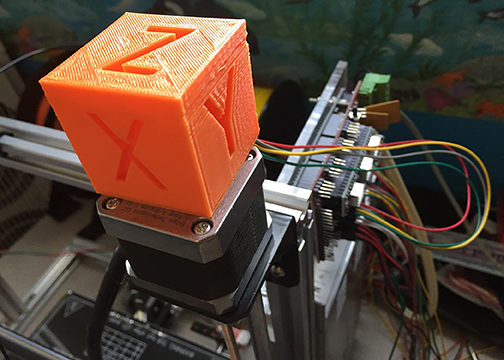 This is a picture of an orange 3-D printed XYZ cube.